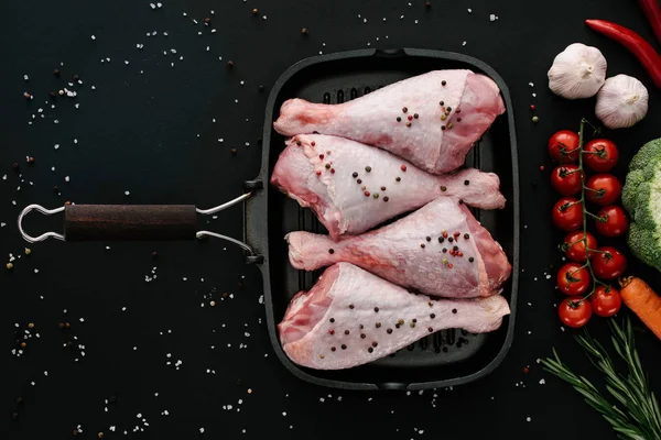 Top view of turkey legs in grill pan with fresh vegetables, salt and pepper corns — Stock Photo