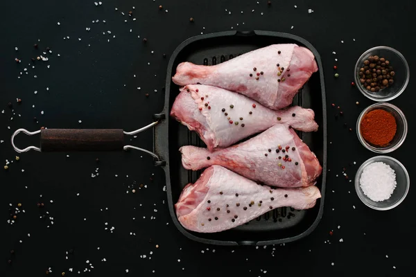 Vue du dessus des cuisses de dinde sur la poêle à griller avec des épices sur la table noire — Photo de stock