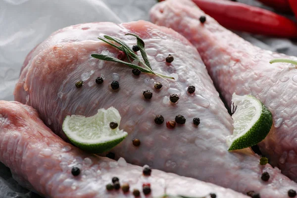Close up view of raw turkey legs with pepper corns and lime — Stock Photo