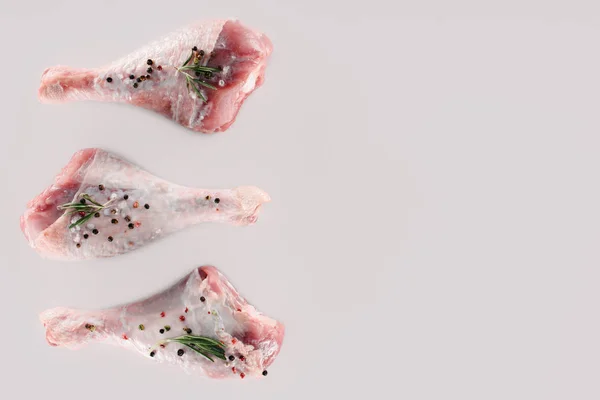 Vista superior de pernas de frango com grãos de pimenta, alecrim e sal isolado em branco — Fotografia de Stock