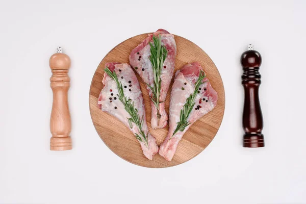 Top view of uncooked turkey legs with rosemary, pepper and salt, isolated on white — Stock Photo