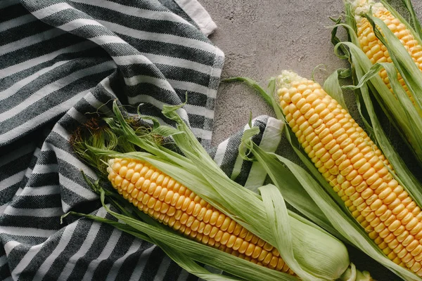 Top view of fresh corn cobs on linen on concrete tabletop — Stock Photo