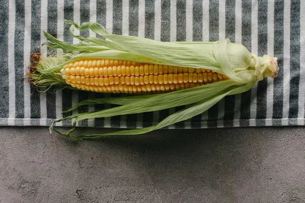 Top view of fresh corn cob on linen on concrete tabletop — Stock Photo