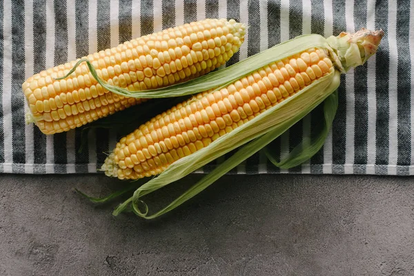 Top view of fresh corn cobs on linen on concrete tabletop — Stock Photo