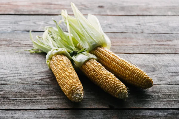 Close up view of fresh ripe corn cobs arranged on wooden surface — Stock Photo