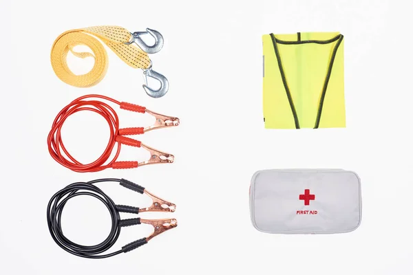 Flat lay with car tow rope, jump start cables, first aid kit and reflective vest isolated on white — Stock Photo