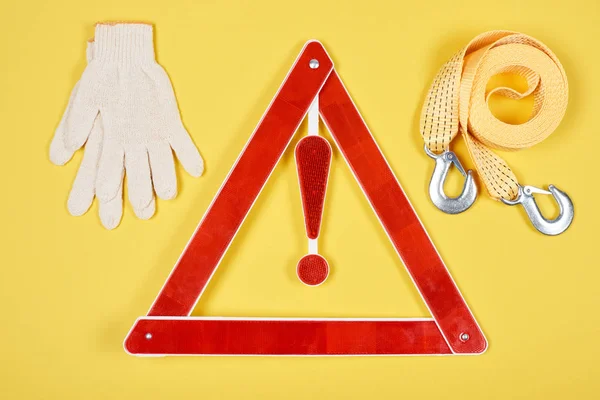 Vue de dessus du triangle d'avertissement panneau routier, gants et câble de remorquage isolé sur jaune — Photo de stock