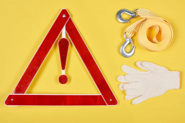 Top view of warning triangle road sign, gloves and car tow rope isolated on yellow — Stock Photo