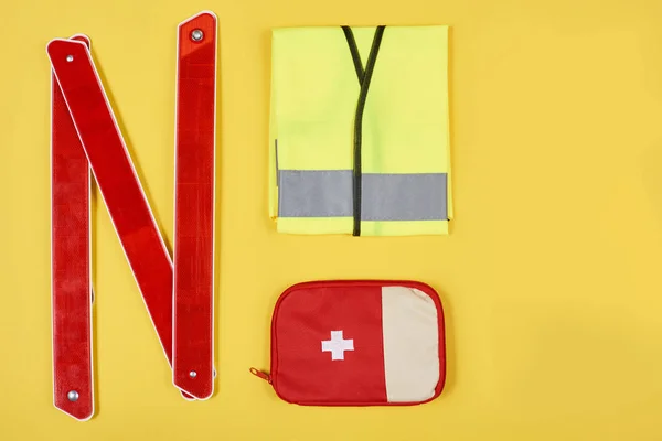 Tendido plano con kit de primeros auxilios arreglado y accesorios de automoción aislados en amarillo - foto de stock