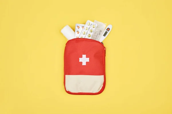 Vue du dessus de la trousse de premiers soins automobile avec différents médicaments isolés sur jaune — Photo de stock