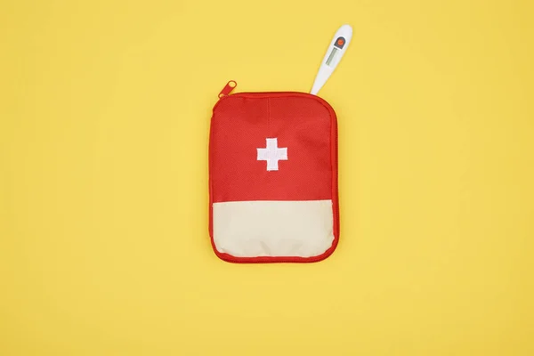 Vue du dessus de la trousse de premiers soins automobile avec thermomètre électronique isolé sur jaune — Photo de stock