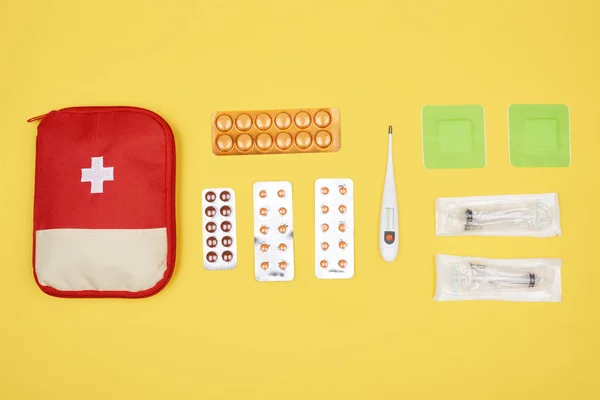 Vista superior del botiquín de primeros auxilios con varios medicamentos aislados en amarillo - foto de stock