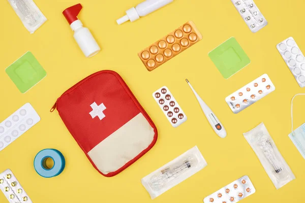 Vue du dessus de la trousse de premiers soins avec divers médicaments isolés sur jaune — Photo de stock