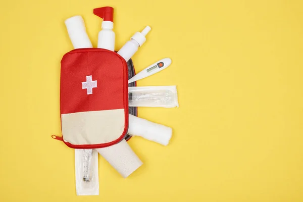 Vista superior do kit de primeiros socorros com vários medicamentos isolados em amarelo — Fotografia de Stock