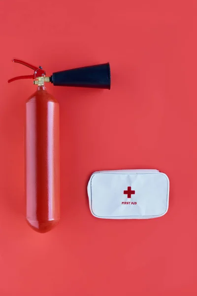 Top view of fire extinguisher and first aid kit isolated on red — Stock Photo