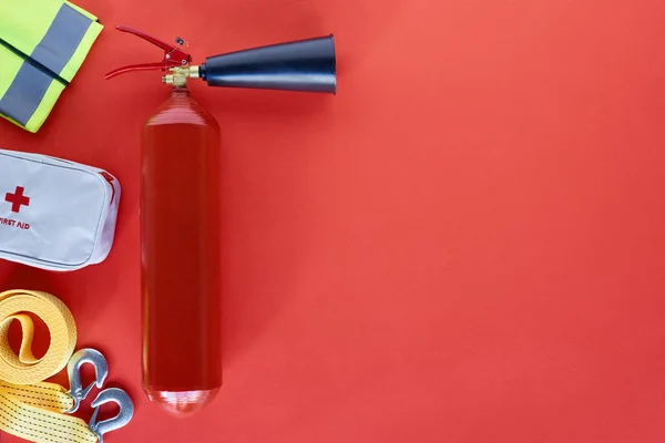 Top view of fire extinguisher and automotive accessories on red backdrop — Stock Photo