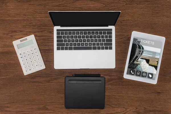 Vue du haut de l'ordinateur portable avec écran vierge, calculatrice, manuel et tablette numérique avec billets à l'écran — Photo de stock