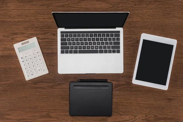 Vue du dessus de l'ordinateur portable, tablette numérique, manuel et calculatrice sur la table — Photo de stock