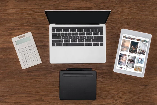 Top view of laptop with blank screen, calculator, textbook and digital tablet with pinterest on screen — Stock Photo