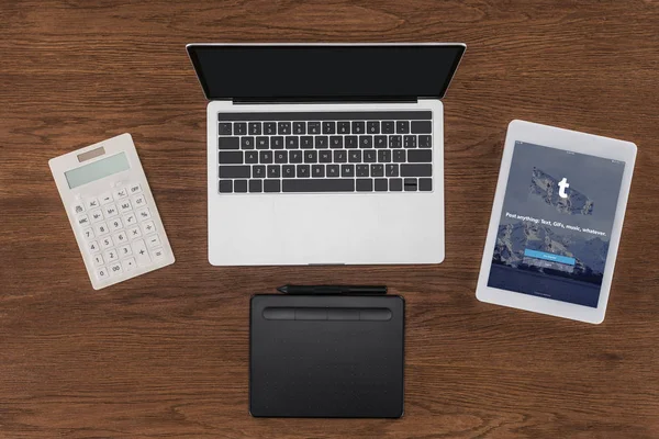 Top view of laptop with blank screen, calculator, textbook and digital tablet with tumblr on screen — Stock Photo