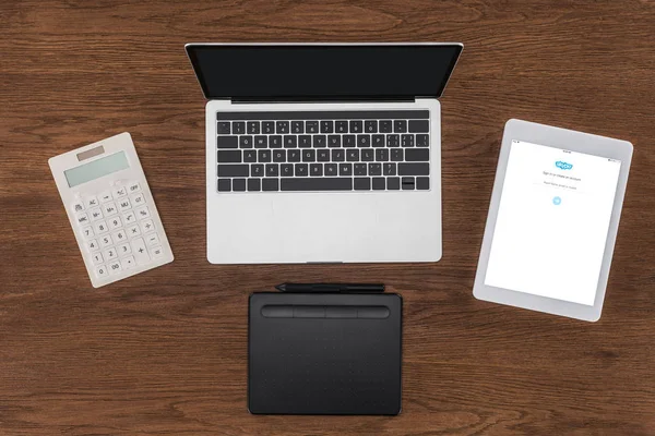 Vista superior do laptop com tela em branco, calculadora, livro didático e tablet digital com skype na tela — Fotografia de Stock