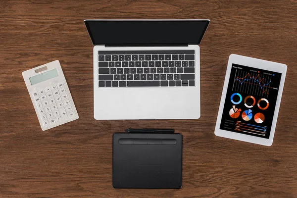 Vista superior do laptop com tela em branco, calculadora, livro didático e tablet digital com gráficos na tela — Fotografia de Stock