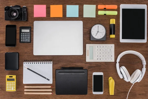 Vista dall'alto del posto di lavoro organizzato con smartphone, laptop, tablet digitale, fotocamere e articoli di cancelleria — Foto stock