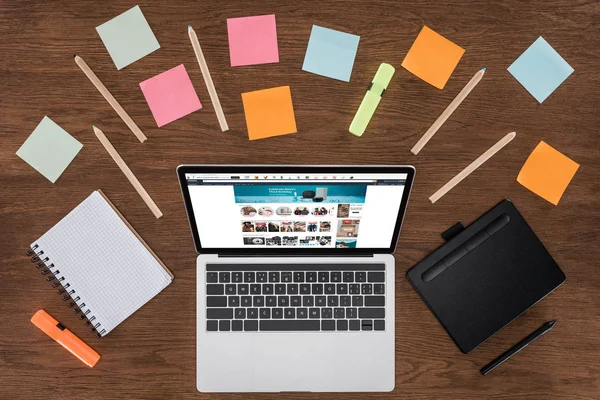 Top view of workplace with arranged textbooks, post it and laptop with amazon on screen — Stock Photo