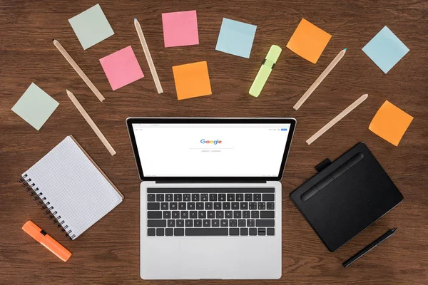 Top view of workplace with arranged textbooks, post it and laptop with google on screen — Stock Photo