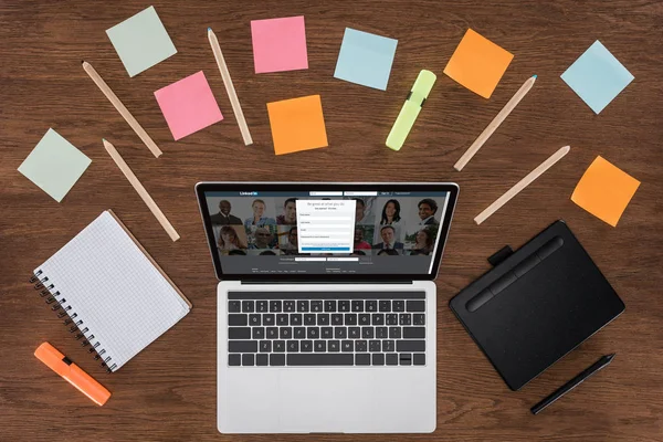 Top view of workplace with arranged textbooks, post it and laptop with linkedin on screen — Stock Photo
