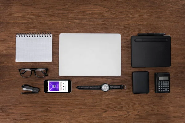 Vista dall'alto del posto di lavoro con libro di testo vuoto organizzato, laptop, orologio da polso e smartphone con applicazione Apple Music sullo schermo — Foto stock