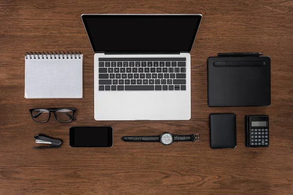 Ansicht des Arbeitsplatzes mit leerem Lehrbuch, Smartphone, Armbanduhr und Laptop mit leerem Bildschirm — Stockfoto