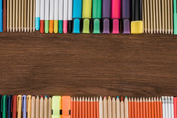 Elevated view of arranged colorful pencils and markers on wooden table — Stock Photo