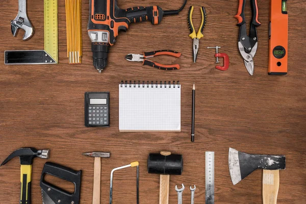 Draufsicht auf leeres Lehrbuch, Taschenrechner und Bleistift, umgeben von verschiedenen Werkzeugen auf Holztisch — Stockfoto