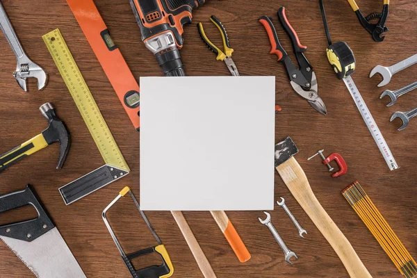 Vista superior de papel vacío cerca dispuesto varias herramientas en la mesa de madera - foto de stock