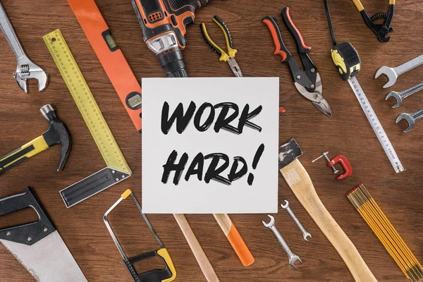 Top view of paper with lettering work hard near arranged various tools on wooden table — Stock Photo