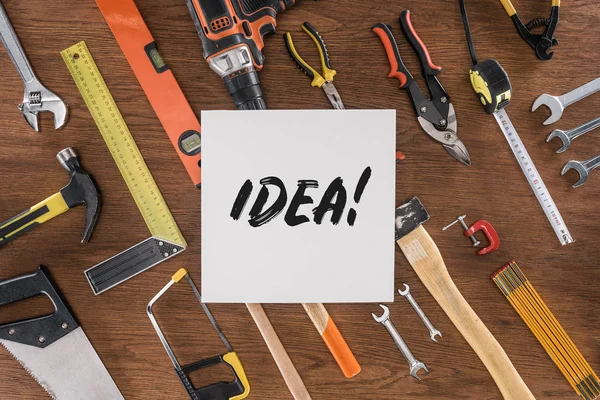 Top view of paper with lettering idea near arranged various tools on wooden table — Stock Photo