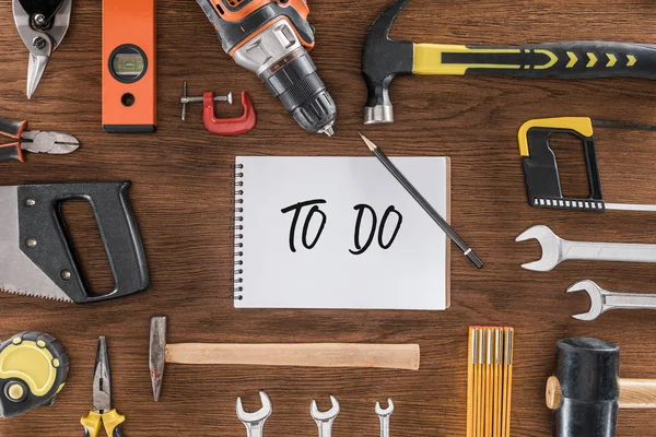 Top view of textbook with lettering to do near various tools on wooden table — Stock Photo