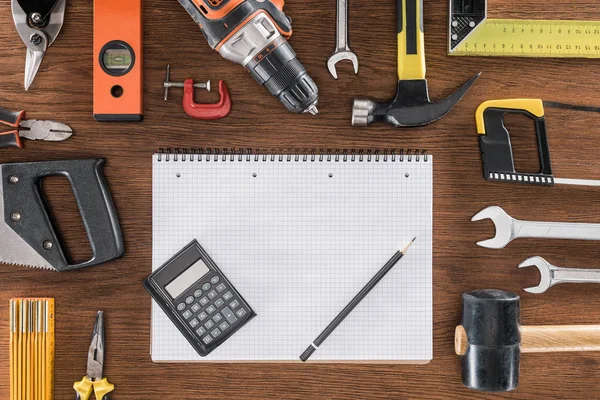 Draufsicht auf leeres Lehrbuch, Taschenrechner und Bleistift, umgeben von verschiedenen Werkzeugen auf Holztisch — Stockfoto