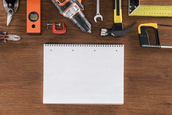 Vue du haut d'un manuel vide près de divers outils disposés sur une table en bois — Photo de stock