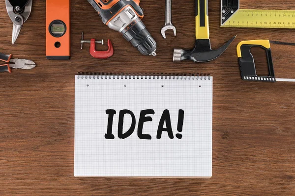 Top view of textbook with lettering idea near various tools on wooden table — Stock Photo