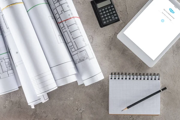 Vista dall'alto dell'architetto posto di lavoro con libro di testo vuoto, calcolatrice e tablet digitale con skype sullo schermo — Foto stock