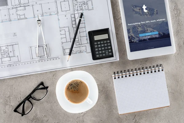 Верхний вид рабочего места архитектора с чертежом, разделителем, кофе и цифровой планшет с tumblr на экране — стоковое фото