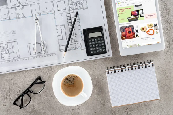 Верхний вид рабочего места архитектора с чертежом, разделитель, кофе и цифровой планшет с Ebay на экране — стоковое фото