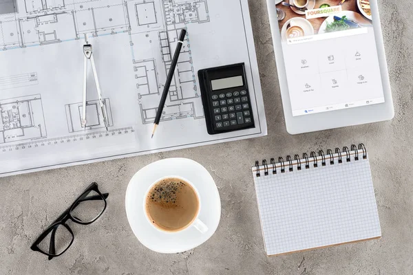 Top view of architect workplace with blueprint, divider, coffee and digital tablet with foursquare on screen — Stock Photo