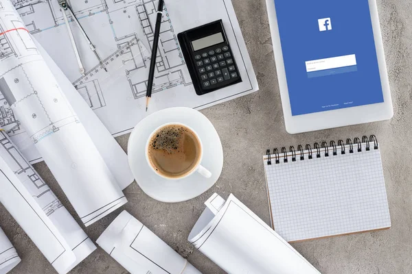 Vue du dessus du lieu de travail de l'architecte avec tasse à café, plans, calculatrice et tablette numérique avec facebook à l'écran — Photo de stock