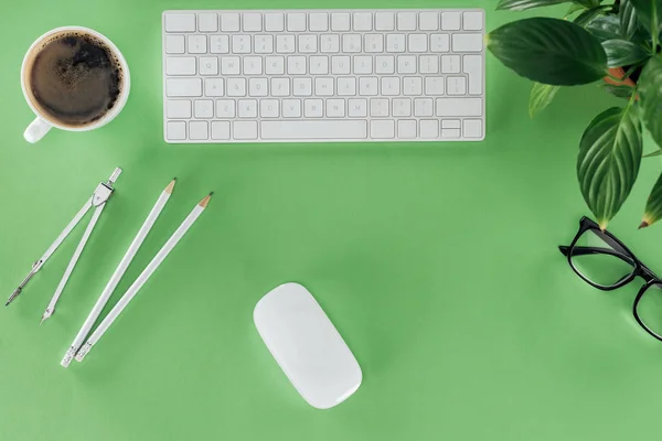 Top view of architect workplace with divider, pencils, coffee and plant on green table — Stock Photo