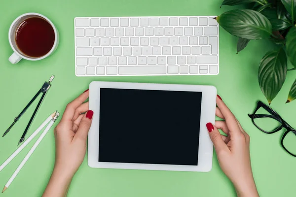 Imagem recortada do arquiteto feminino segurando tablet digital com tela em branco na mesa com divisor, café e vaso planta — Fotografia de Stock