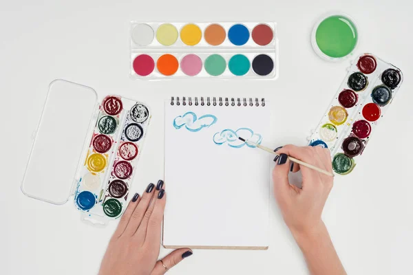 Zugeschnittenes Bild einer Malerin, Zeichnung mit dem Pinsel im Lehrbuch am weißen Tisch mit bunten Farben — Stockfoto