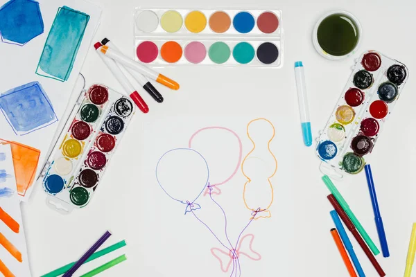 Top view of artist workplace with colorful paints, markers and painting of air balloons on white table — Stock Photo